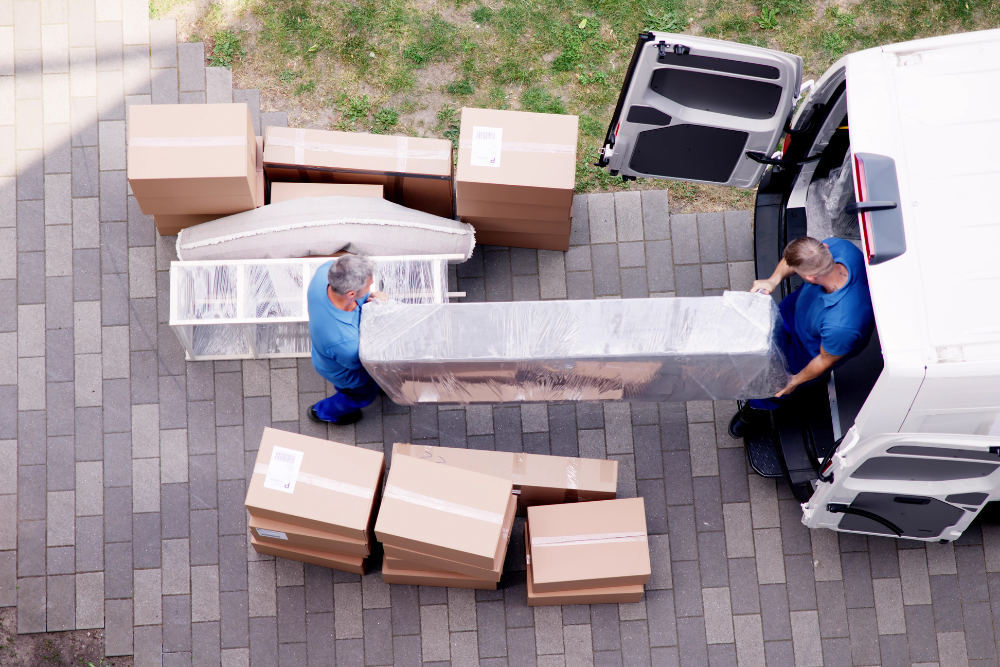 Team members carrying an old mattress out of a residential home for furniture removal service.